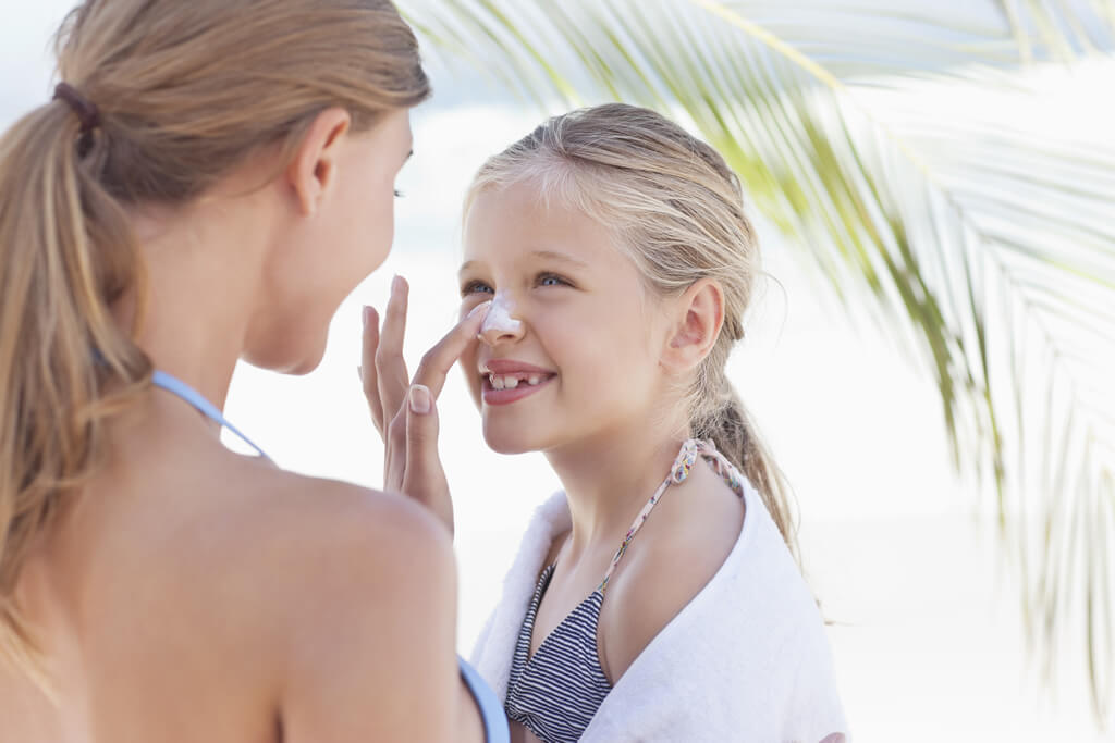 Woman applying sunscreen on daughter's nose